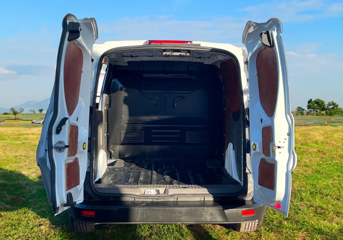a Ford Transit Connect with its doors open in a field.