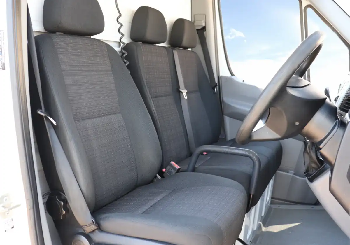 the interior of a Mercedes Sprinter Tipper with black leather seats.