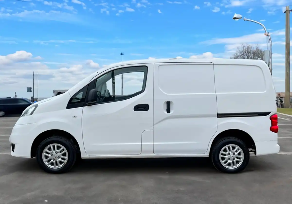 a white Nissan NV200 parked in a parking lot.
