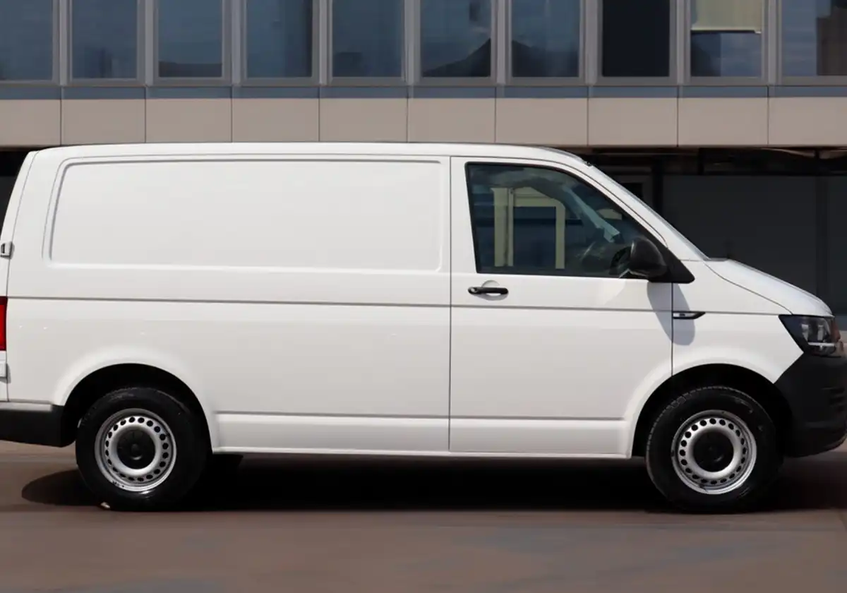 a white Volkswagen Transporter parked in front of a building.