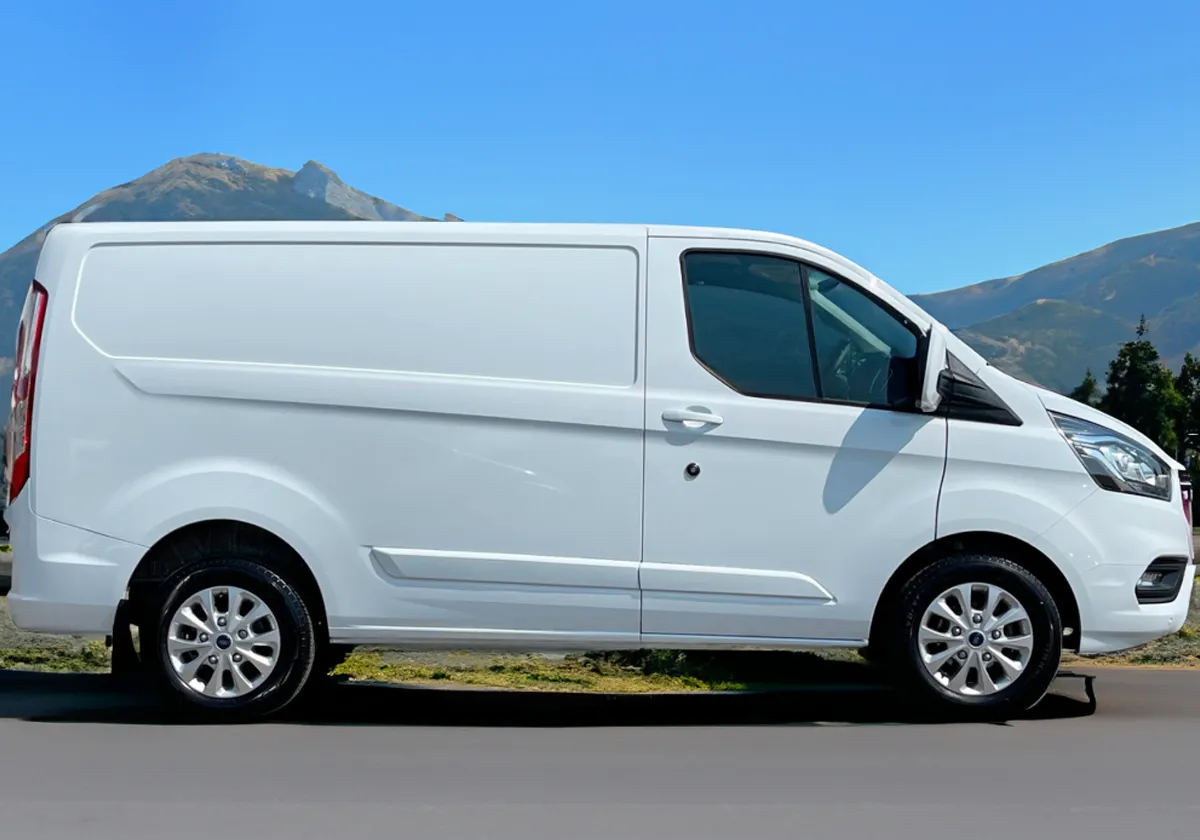a white Ford Transit Custom parked in front of mountains.