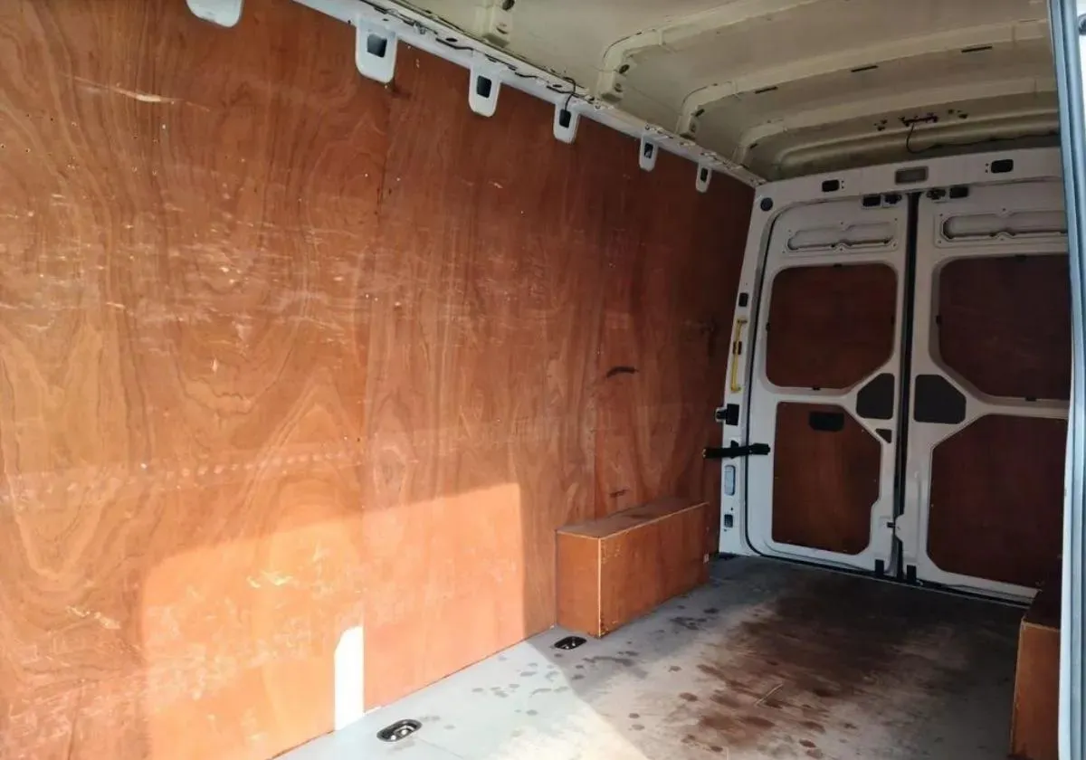 An open back sliding door of a Volkswagen Crafter, revealing a wooden floor and walled cargo hold.